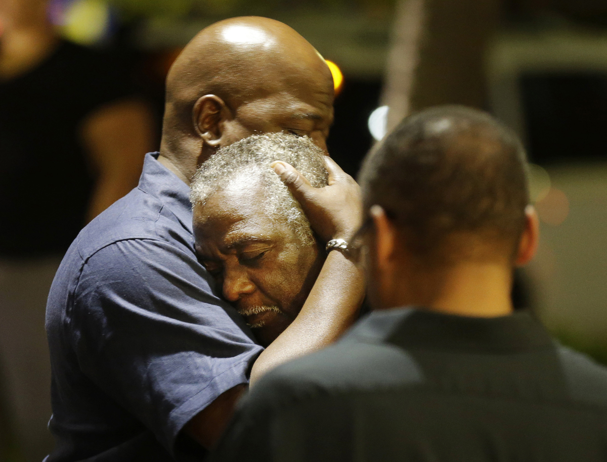 Worshippers embrace following a group prayer across the street from the scene of the shooting. A white man opened fire during