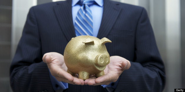 Businessman stands holding a golden piggy bank cradled in his hands