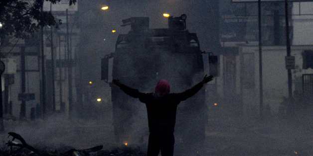 Un manifestant vénézuélien face à un char anti-émeute à Caracas