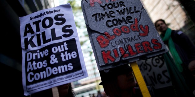 Protesters carry placards during a protest against multinational IT firm and Paralympics sponsor Atos outside the company's head office in London on August 31, 2012. Protesters are outside Atos to protest there involvement in the tests on incapacity benefit claimants that has been awarded to them by the Department of Work and Pensions. Disabled and anti-cuts campaigners have been rallying as they claim the tests for people on disability by Atos are 'damaging and distressing'. AFP PHOTO / ANDREW