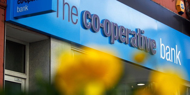 A sign sits above the entrance to a Co-Operative Bank Plc bank branch in Altrincham, U.K., on Tuesday, March 11, 2014. Co-Operative Group Ltd. Chief Executive Officer Euan Sutherland offered to resign after he publicly complained that a board member may have leaked details about his pay, according to a person with knowledge of the matter. The Co-Op Group were forced in October 2013 to give up control of Co-Operative Bank Plc to help plug a 1.5 billion pound capital hole at the division. Photogra