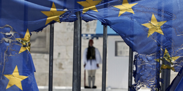 A Greek presidential guard stands as he seen through the remains of a European Union flag half-burnt by protesters in Athens, on Wednesday, May 1, 2013. About 8,000 people took part in subdued demonstrations in Athens as austerity-weary unions held a strike for May Day. The countryâs main labor unions protested soaring unemployment, which is the highest in the 27-country European Union, and the austerity measures the conservative-led government is enacting in return for crucial bailout loans. (AP Photo/Petros Giannakouris)