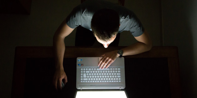 Guy checking internet with laptop at late night with dark room, view from above. Internet addiction.