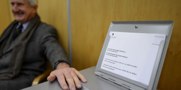 An usher guards the ballot box on November 30, 2014 in the old town of Fribourg. The Swiss voted early Sunday in three national referendums, including one calling for dramatic immigration cuts in the name of saving the environment, in polling open for just two hours. Most voters, however, had already cast their ballots by mail, and initial results were expected to be available shortly after polling stations closed at noon. AFP PHOTO / FABRICE COFFRINI (Photo credit should read FABRICE CO