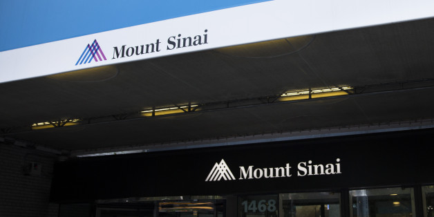 A medical worker and police officer stand outside Mount Sinai Medical Center where a male patient with a high fever and gastrointestinal symptoms is undergoing testing for the Ebola virus following a recent trip to West Africa, Monday, Aug. 4, 2014, in New York. The report comes as officials at U.S. airports are watching travelers from Africa for flu-like symptoms that could be tied to the recent Ebola outbreak. (AP Photo/John Minchillo)