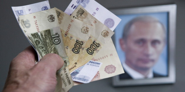 GERMANY, BONN - DECEMBER 02:Â Hand with russian ruble banknotes and a framed Putin photo in the background, on December 02, 2014 in Bonn, Germany. (Photo by Ulrich Baumgarten via Getty Images)