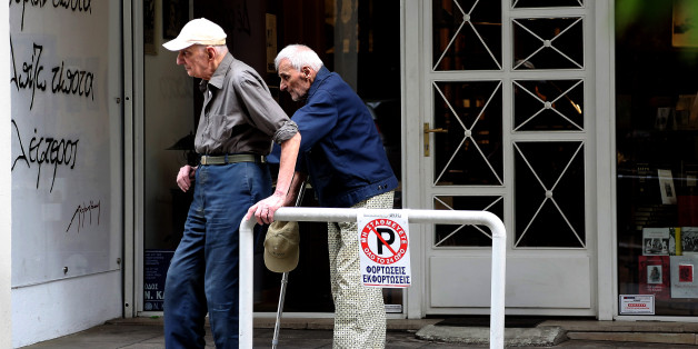 Two elderly men help one another on a sidewalk outside a bookstore in central Athens, Monday, June 2, 2014. Greece is facing renewed international pressure to press ahead with long-term cost-cutting measures, despite meeting key targets set by bailout lenders for austerity measures that have caused widespread hardship in the troubled eurozone member. The writing on the wall reads âI hope for nothing. I fear nothing. I am freeâ, from the epitaph on the grave of Nikos Kazantzakis, the renowned Greek novelist and author of âZorba the Greekâ (AP Photo/Dimitris Messinis)
