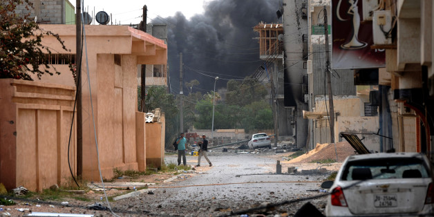 Libyan rebels are seen walking down a street close to a building where forces loyal to Col. Moamer Kadhafi are reportedly held up in the Zwabi district of Misrata on April 24, 2011, as rebels accuse Kadhafi of playing dirty games in the city where salvos of Grad rockets explode in apparent contradiction of his regime's vow to halt fire. AFP PHOTO/CHRISTOPHE SIMON (Photo credit should read CHRISTOPHE SIMON/AFP/Getty Images)