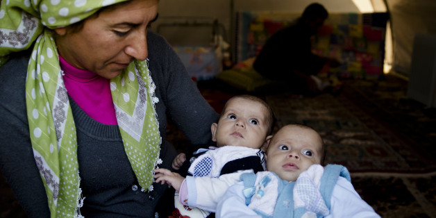 A Syrian Kurdish refugee woman from the Kobani area holds two babies at a camp in Suruc, on the Turkey-Syria border Wednesday, Nov. 19, 2014. Kobani, also known as Ayn Arab, and its surrounding areas, has been under assault by extremists of the Islamic State group since mid-September and is being defended by Kurdish fighters. (AP Photo/Vadim Ghirda)