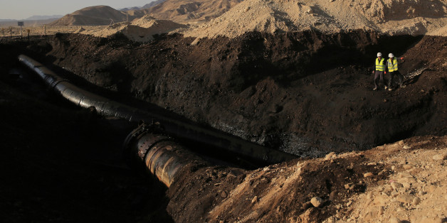 Employees of the Trans-Israel Pipeline clean up the large deposits of crude oil that gushed out of a breached pipeline near the southern Israeli village of Beer Ora, north of Eilat, Friday, Dec. 5, 2014. Israel says a breached pipeline has caused a large oil spill in the southern part of the country. The spill occurred when the pipeline, linking Eilat to the port city of Ashkelon on the Mediterranean Sea, burst. The spill occurred in a dramatic desert landscape featuring steeply rising cliffs ne