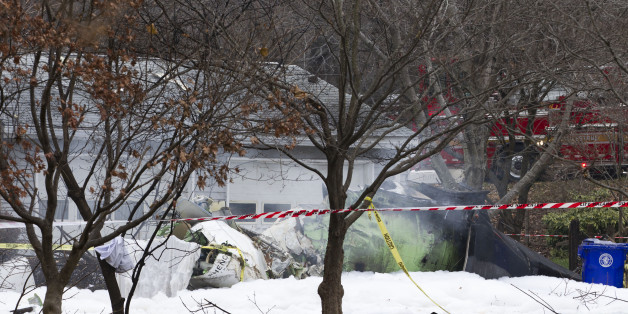 The wreckage of a small private jet smolders in a driveway after crashing into a neighboring house in Gaithersburg, Md., Monday, Dec. 8, 2014. A woman and her two young sons inside the home and three people aboard the aircraft were killed, authorities said. (AP Photo/Jose Luis Magana)