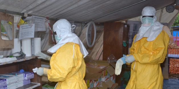 Guinea's health workers wearing protective suits put on gloves at an Ebola Donka treatment centre in Conakry on December 8, 2014. The European Union said it had given an extra 61 million euros in aid to help fight the Ebola crisis raging in west Africa. The Ebola outbreak ravaging Guinea, Liberia and Sierra Leone has claimed more than 6,300 lives, with health authorities in Conakry having registered more than 1,400 deaths. AFP PHOTO/CELLOU BINANI (Photo credit should read CELLOU BINANI/AFP/Getty Images)