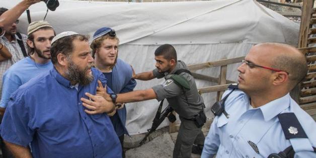 Un garde-frontière repousse des membres de Lehava, dont le chef Bentzi Gopstein (2e à g), qui tentent d'accéder à l'esplanade des Mosquées, temporairement fermée au public, le 30 octobre 2014