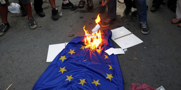 Protesters burn an EU flag during an anti-bailout protest outside of Cyprus' parliament in Nicosia, Tuesday, April 30, 2013. Cyprus' lawmakers are voting Tuesday on a multi-billion bailout agreement aimed at preventing the country from going bankrupt. The 56-seat parliament is expected to narrowly approve the 23 billion-euro ($30 billion) deal that the country struck with its euro partners and the International Monetary Fund last month. (AP Photo/Petros Karadjias)