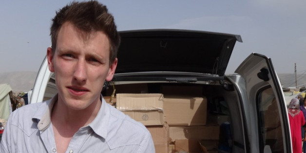 This undated photo provided by Kassig Family shows Peter Kassig standing in front of a truck filled with supplies for Syrian refugees. Confronted by terrorists beheading Americans, President Barack Obama has ordered a review of how the United States responds when citizens are taken hostage overseas. (AP Photo/Courtesy Kassig Family)