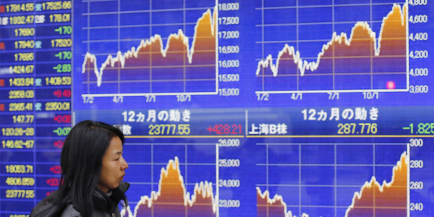 A woman walks past an electronic stock indicator of a securities firm in Tokyo, Monday, Dec. 29, 2014. Asian stocks were mostly higher Monday after a report China will change banking rules in an apparent effort to boost lending and economic growth as oil prices rebounded. (AP Photo/Shizuo Kambayashi)