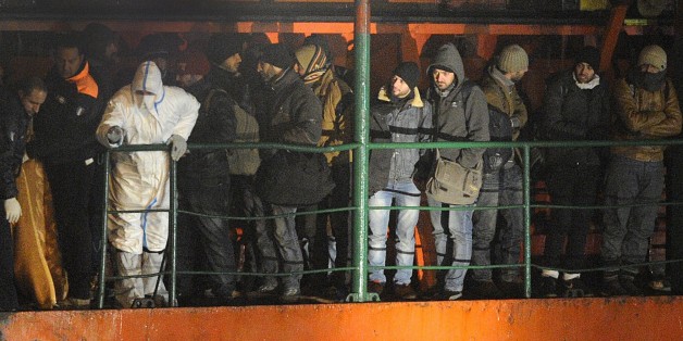 Migrants wait early on December 31, 2014 aboard the Moldovan-flagged ship Blue SKy M. in the port of Gallipoli, in southeastern of Italy. Some 700 illegal migrants rescued from the ship near the Greek island of Corfu arrived in Italy on December 31 after their boat was intercepted while drifting towards the coast. Police and maritime authorities will investigate how the migrants, reportedly mainly from Syria, came to be hidden on the Blue Sky M as it sailed to the Croatian port of Rijeka. AFP PHOTO / NUNZIO GIOVE (Photo credit should read NUNZIO GIOVE/AFP/Getty Images)
