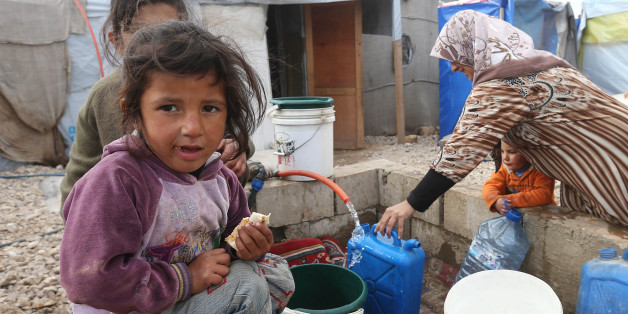 A Syrian girl eats a sandwich as others fill water containers at a refugee camp in Deir Zannoun village, Bekaa valley, Lebanon, Tuesday, Jan. 6, 2015. A snow storm is expected to hit Lebanon affecting Syrian refugees, many of whom live in tents without heating. The government estimates there are about 1.5 million Syrians in Lebanon, about one-quarter of the total population. (AP Photo/Hussein Malla)