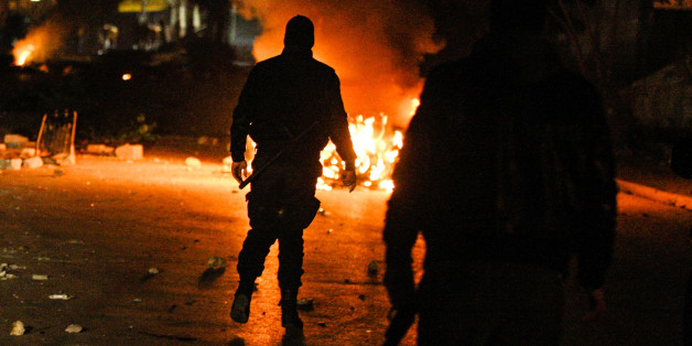 Tunisian Police officers walks in a street during clashes with riot police close to a tax office in Ettadhamen,Tunisia, 5 kms (3 miles) from Tunis, Friday, Jan. 10, 2014. Clashes erupted in Ettadhamen, near Tunis late Friday evening between police and demonstrators as discontent mounts over new taxes levied by the government late Friday. (AP/Aimen Zine)