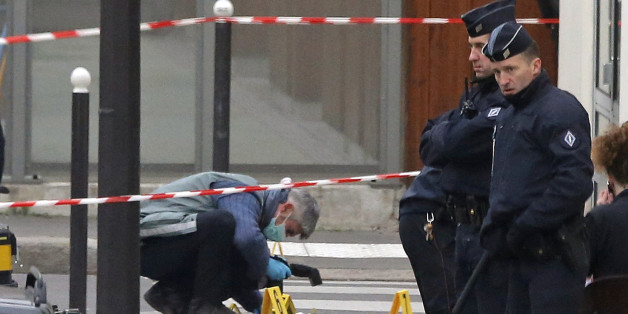 French investigating police officer takes photos outside the door of the French satirical newspaper Charlie Hebdo's office, in Paris, Wednesday, Jan. 7, 2015. Masked gunmen stormed the offices of a French satirical newspaper Wednesday, killing at least 11 people before escaping, police and a witness said. The weekly has previously drawn condemnation from Muslims. (AP Photo/Francois Mori)