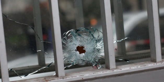 A bullet impact is seen in a window of a building next to the French satirical newspaper Charlie Hebdo's office, in Paris, Wednesday, Jan. 7, 2015. Masked gunmen shouting "Allahu akbar!" stormed the Paris offices of a satirical newspaper Wednesday, killing at least 12 people, including the paper's editor, before escaping in a getaway car. (AP Photo/Thibault Camus)