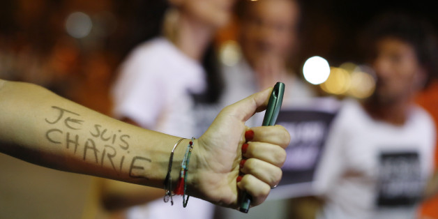 A woman holding a pen shows her arm covered with the words in French "I am Charlie" at a gathering in solidarity with those killed in an attack at the Paris offices of the weekly newspaper Charlie Hebdo, in a plaza in Rio de Janeiro, Wednesday, Jan. 7, 2015. Masked gunmen stormed the offices of the satirical newspaper that caricatured the Prophet Muhammad, killing 12 people Wednesday, including the editor, before escaping in a car. It was France's deadliest postwar terrorist attack. (AP Photo/Le