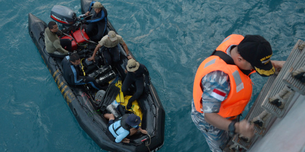 Indonesian navy divers in a boat prepare for operations to lift the tail of AirAsia Flight 8501 in Java sea, Indonesia Friday, Jan. 9, 2015. Days after sonar detected apparent wreckage, an unmanned underwater vehicle showed the plane's tail, lying upside down and partially buried in the ocean floor. (AP Photo/Adek Berry, Pool)