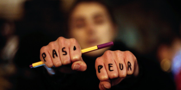 A woman holds up her hands bearing the words "Not afraid" in French during a gathering in solidarity of the victims of a terror attack against French satirical newspaper Charlie Hebdo in Paris, Wednesday, Jan. 7, 2015. Masked gunmen stormed the Paris offices of a weekly newspaper that caricatured the Prophet Muhammad, methodically killing 12 people Wednesday, including the editor, before escaping in a car. It was France's deadliest postwar terrorist attack. (AP Photo/Thibault Camus)