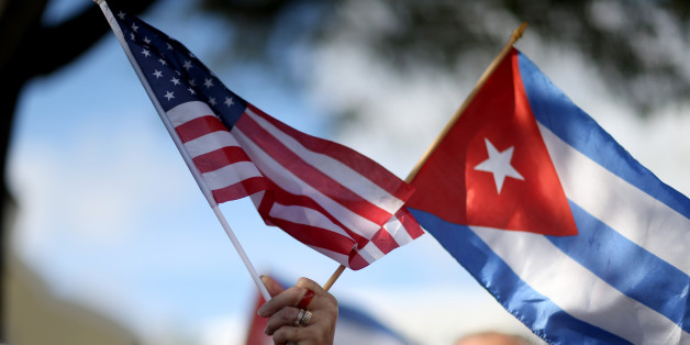 MIAMI, FL - DECEMBER 20: A protester holds an American flag and a Cuban one as she joins with others opposed to U.S. President Barack Obama's announcement earlier in the week of a change to the United States Cuba policy stand together at Jose Marti park on December 20, 2014 in Miami, Florida. President Obama announced a move toward normalizing the relationship with Cuba after a swap of prisoners took place. (Photo by Joe Raedle/Getty Images)