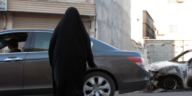 A man inspects a burned vehicle in the eastern town of al-Awamiya, Saudi Arabia, Saturday, Dec. 20, 2014, where shooting took place. Saudi Arabia's Interior Ministry says government forces have shot and killed four gunmen in a restive eastern town that is heavily populated by minority Shiites. (AP Photo)