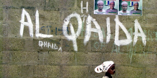 FILE - In this April 18, 2003, file photo a girl walks past a wall with graffiti about the al-Qaida network in a Muslim area of the northern city of Kano, Nigeria. Al-Qaida's terror network in North Africa, which calls itself Al-Qaida in the Islamic Maghreb (AQIM), is growing more active and attracting new recruits, and threatening to further destabilize fragile governments of heavily-Islamic North Africa, according to U.S. defense and counterterrorism officials. (AP Photo/Schalk van Zuydam, File)