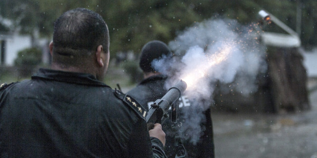 FILE - In This Jan. 31, 2014 photo a riot police officer fires a tear gas canister during clashes with Salafists in the Djebel Lahmar neighborhood near Tunis, Tunisia . Mosques are being closed down, local organizations banned and at least 1,000 have been arrested as Tunisia carries out a wide-ranging crackdown against those suspected of sympathizing with radical Islamists. While still one of the only democracies to emerge from the Arab Spring uprisings, Tunisia's battle against terrorism is raising fears that it might be returning to its bad old days of political repression. (AP Photo/Aimen Zine, File)