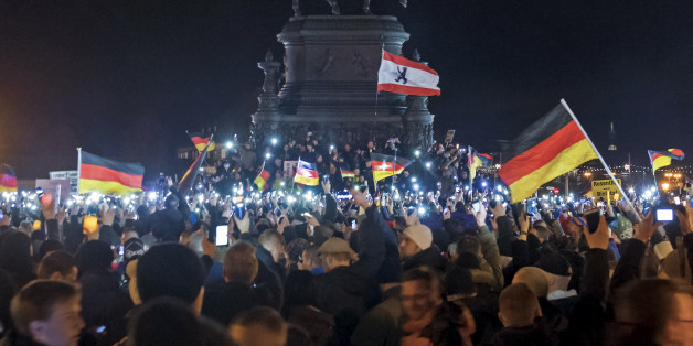 Participants of a rally called 'Patriotic Europeans against the Islamization of the West' (PEGIDA) hold German flags and lights during a demonstration entitled âChristmas With Pegidaâ in front of the bronze equestrian statue of King John of Saxony in Dresden, eastern Germany, Monday, Dec. 22, 2014. For the past ten weeks, activists protesting Germanyâs immigration policy and the spread of Islam in the West have been marching each Monday. (AP Photo/Jens Meyer)