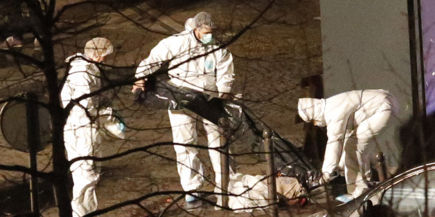 Police officers remove a body lying outside the kosher market, in Paris, Friday Jan. 9, 2015. What started as a hunt for two terror suspects took on an even graver focus Friday as French police grappled with a potential terrorist cell. The suspects knew each other, had been linked to previous terrorist activities, and one had fought or trained with Al Qaida in Yemen. (AP Photo/Francois Mori)