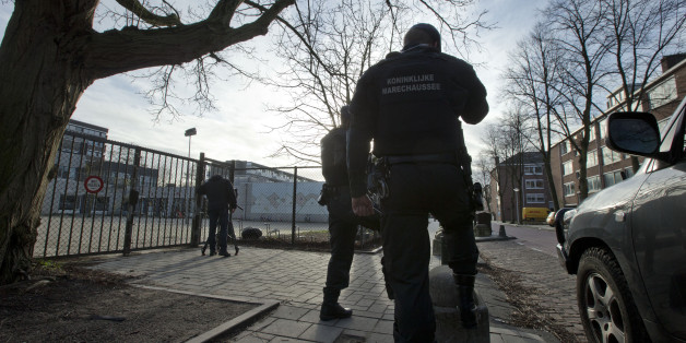 Military police officers guard Cheider Orthodox Jewish school, rear left, at the gates of the closed school in Amsterdam, Netherlands, Friday, Jan. 16, 2015. The school was closed Friday after Belgium raised its terrorist threat level following a shootout in the city of Verviers. More than two dozen suspects have been arrested in Belgium, France and Germany in continuing searches for suspected terrorists, authorities said Friday. Thirteen people were detained in Belgium and two arrested in France in an anti-terror sweep following a firefight in which two suspected terrorists were killed, and more suspects are being sought, Belgian authorities said. (AP Photo/Peter Dejong)