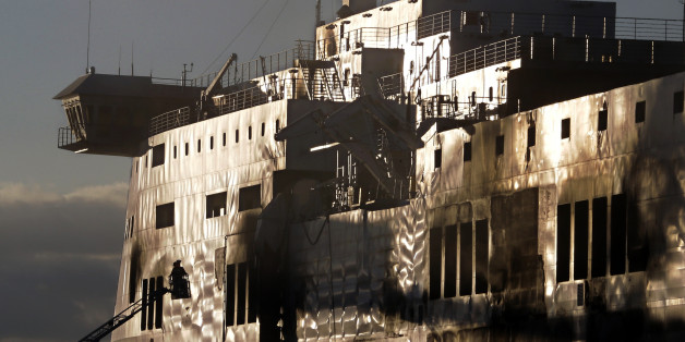 A fireman works outside the Norman Atlantic ferry after that has been towed into the port of Brindisi, southern Italy, Friday, Jan. 2, 2015. The blaze that broke out Sunday and torched the ferry has killed at least 11 people and authorities prepared to search it for possible more dead. Italy says 477 people were rescued, most by helicopters that plucked survivors off the top deck in gale-force winds and carried them to nearby boats. (AP Photo/Antonio Calanni)