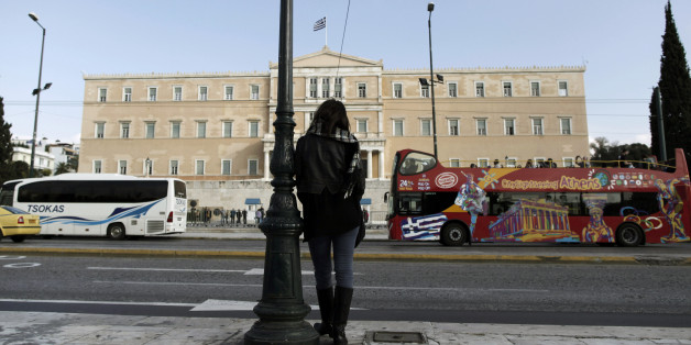 A woman stands opposite the Parliament in central Athens, Tuesday, Nov. 27, 2012. Greece has avoided imminent bankruptcy after its international creditors finally agreed early Tuesday to give it the money it urgently needs. But the cash-strapped country's economic distress is likely to drag on for years to come.(AP Photo/Petros Giannakouris)
