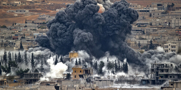 FILE - In this Monday, Nov. 17, 2014 file photo, smoke rises from the Syrian city of Kobani, following an airstrike by the U.S.-led coalition, seen from a hilltop outside Suruc, on the Turkey-Syria border. Syrian activists and Kurdish officials say the extremist Islamic State group has been nearly pushed out of the Syrian border town of Kobani. (AP Photo/Vadim Ghirda, File)