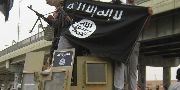 FILE - In this Sunday, March 30, 2014, file photo, Islamic State group militants hold up their flag as they patrol in a commandeered Iraqi military vehicle in Fallujah, 40 miles (65 kilometers) west of Baghdad, Iraq. Human Rights Watch on Thursday, Jan. 29, 2015 blasted Islamic State militants over their atrocities, but also criticized the Syrian and Iraqi governments over what the New York-based group described as "sectarian and abusive" policies that fuel extremism. (AP Photo, File)