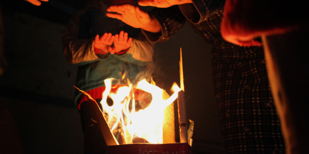 In the early morning, Syrian refugee children warm their hands up with a fire made out of wood in a steel canister in a deserted building where they live with their families during a snowstorm in Amman, Jordan, Thursday, Dec. 12, 2013. Snow blanketed most regions of Jordan, blocking highways in the south, causing power cuts across the capital and closing down schools and government offices. However, the northern parts of the country, including a district hosting the Zaatari Camp for Syrian refugees, only received rain. (AP Photo/Mohammad Hannon)
