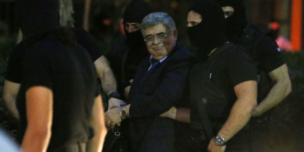 Leader of the extreme far-right Golden Dawn party, Nikos Michaloliakos, center, smiles toward his supporters as he escorted by anti-terror police upon his arrival to a court for a preliminary hearing into charges of participating in a criminal organization in Athens, Wednesday, Oct. 2, 2013. Three lawmakers from Greece's extremist right-wing Golden Dawn party were released from custody Wednesday pending trial, after they provided initial testimony in criminal investigation triggered by the slayi