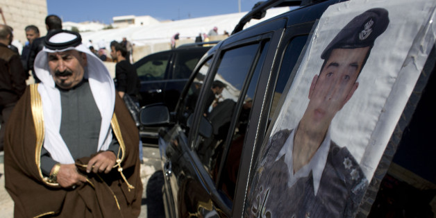 A Jordanian man walks past a poster that is pasted on a vehicle with a picture of slain Jordanian pilot, Lt. Muath al-Kaseasbeh with Arabic that reads, "we are all Muath," at his home village of Ai, near Karak, Jordan, Wednesday, Feb. 4, 2015. Outrage and condemnation poured across the Middle East on Wednesday as horrified people learned of the video purportedly showing the Islamic State group burn a Jordanian pilot to death. (AP Photo/Nasser Nasser)