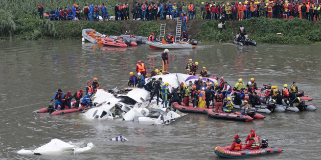 Emergency personnel try to extract passengers from a commercial plane after it crashed in Taipei, Taiwan, Wednesday, Feb. 4, 2015. The Taiwanese commercial flight with 58 people aboard clipped a bridge shortly after takeoff and crashed into a river in the island's capita on Wednesday morning. (AP Photo/Wally Santana)
