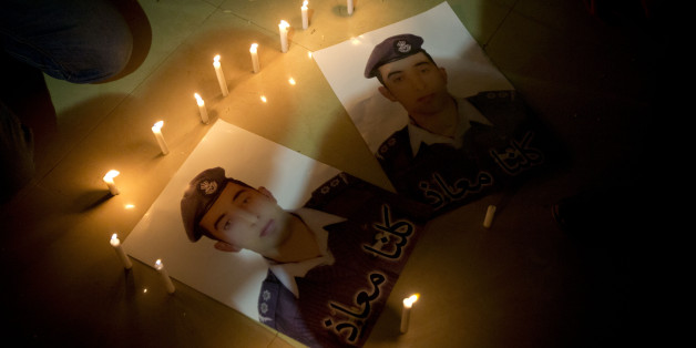 Members of Al-Kaseasbeh, the tribe of Jordanian pilot, Lt. Muath al-Kaseasbeh, who is held by the Islamic State group militants, light candles by posters with his picture and Arabic that reads "we are all Muath," at the captured pilot's tribal gathering divan, in his home town of Karak, Jordan, Saturday, Jan. 31, 2015. An online video released Saturday night purported to show an Islamic State group militant behead Japanese journalist Kenji Goto, ending days of negotiations by diplomats to save t