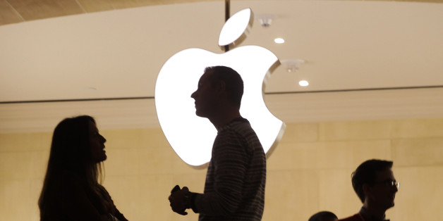 Apple employees stand near the Apple logo at the company's new store in Grand Central Terminal, Wednesday, Dec. 7, 2011 in New York. (AP Photo/Mark Lennihan)