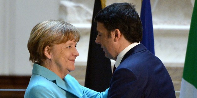 Italian Prime Minister Matteo Renzi (R) hugs German Chancellor Angela Merkel beneath the original 16th century statue of David by Italian artist Michelangelo Buonarroti during a joint press conference in the Galleria dell'Accademia in central Florence on January 23, 2015. The eurozone's deep divisions were set to be given an airing as Italian Prime Minister hosted German Chancellor Angela Merkel days before crucial elections in Greece. AFP PHOTO / ALBERTO PIZZOLI (Photo credit should read