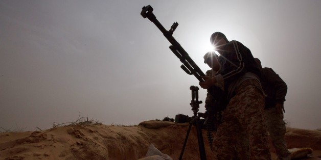 In this Saturday, Feb. 21, 2015 photo, Libyan soldiers try to fix a weapon that jammed during clashes with militants on the frontline in Al Ajaylat, 120 kilometers (75 miles) west of Tripoli, Libya. Army forces in Libya have been fighting Islamic and tribal militias since last September. (AP Photo/Mohamed Ben Khalifa)