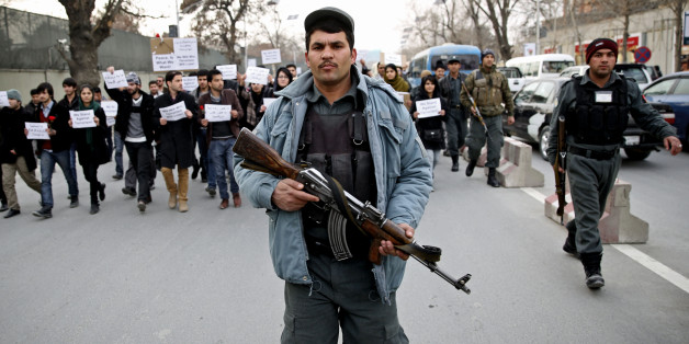 An Afghan police walks ahead of members of civil society organizations for their protection as they march in a street, during an anti terrorism demonstration in Kabul, Afghanistan, Sunday, Jan. 19, 2014. Hundreds of Afghans gathered outside a Lebanese restaurant in Kabul on Sunday to protest against Taliban attack that killed 21 people. The assault Friday by a Taliban bomber and two gunmen against the La Taverna du Liban restaurant was deadliest single attack against foreign civilians in the course of a nearly 13-year U.S.-led war there now approaching its end. They chanted slogans against terrorism as they laid flowers at the site of the attack. The dead included 13 foreigners and eight Afghans, all civilians. The attack came as security has been deteriorating and apprehension has been growing among Afghans over their country's future as U.S.-led foreign forces prepare for a final withdrawal at the end of the year. (AP Photo/Massoud Hossaini)
