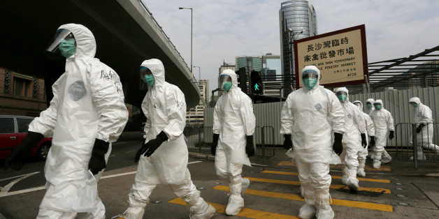 Health workers in full protective gear walk at a wholesale poultry market before culling the poultry in Hong Kong, Tuesday, Jan. 28, 2014. Hong Kong authorities began culling 20,000 birds at a wholesale market after poultry from southern mainland China tested positive for the H7N9 virus, the first time it had been found in imported poultry in Hong Kong. (AP Photo/Vincent Yu)