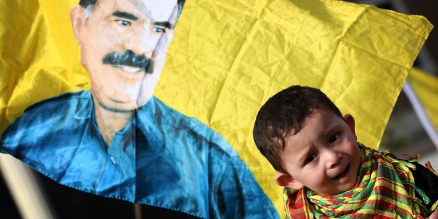 A child is seen in front of a flag bearing a portrait of the leader of the Kurdistan Workers Party (PKK) Abdullah Ocalan during a demonstration calling for his release on February 15, 2015 outside the Turkish consulate in Arbil, the capital of the autonomous Kurdish in Arbil. Ocalan was captured by Turkish undercover agents in Kenya in 1999, brought back to Turkey and sentenced to death. His sentence was later commuted to life. AFP PHOTO / SAFIN HAMED (Photo credit should read SAFIN HAME